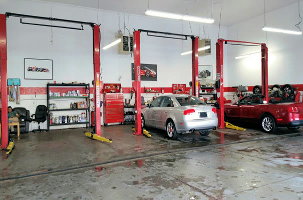 Inside the shop, three red two post lifts with the parts shelves and tool chests along the back wall